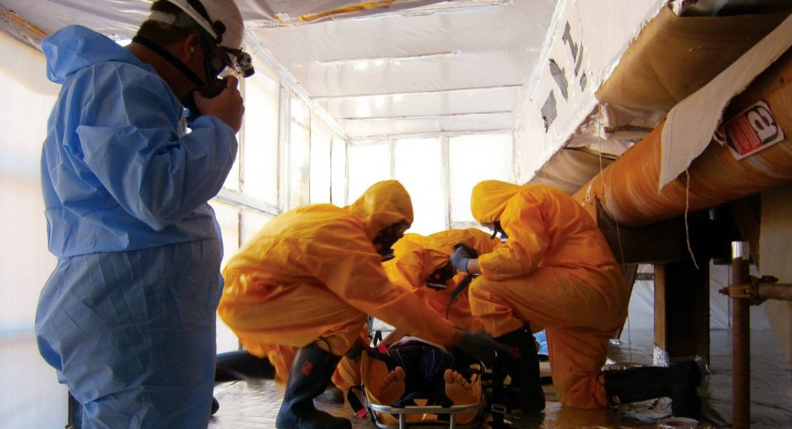 Three people in protective suites performing removal works