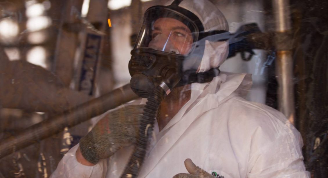 Man wearing protective suit and air filter mask during deconstruction project